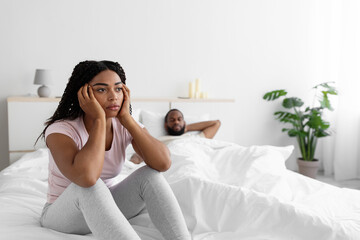 Obraz na płótnie Canvas Sad young african american woman is sad and ignores her husband after scandal in comfortable bed