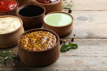 Many different sauces on wooden table, space for text