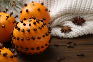 Pomander balls made of tangerines with cloves on wooden table, closeup