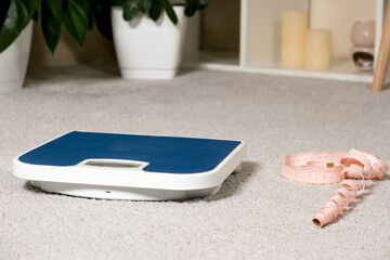 Floor blue scales and centimeter measuring tape on a gray carpet in the interior. The idea of losing weight and losing weight.