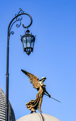 A sculpure of an angel alongside an ornate lamp-post adornes the top of a memorial to the dead at La recoleta Cemetery in Buenos Aires