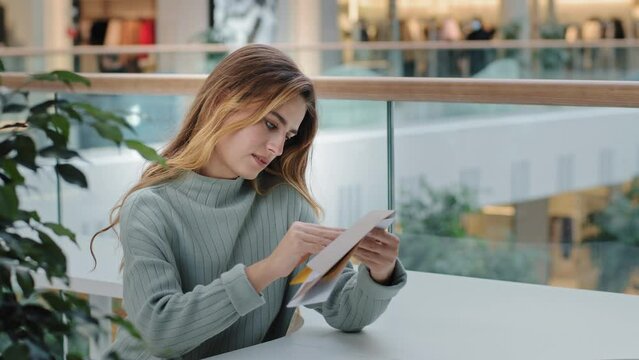Caucasian millennial woman recipient girl sitting cafe company office shopping mall having correspondence opening letter envelope reads test results bank notice news offer insurance statement account