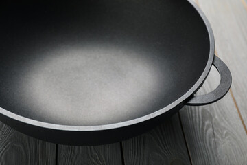 Empty iron wok on grey wooden table, closeup. Chinese cookware