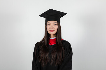 Smiling graduate student in mortar board and bachelor gown on white background