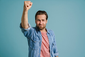 Young furious man frowning while shaking his fist