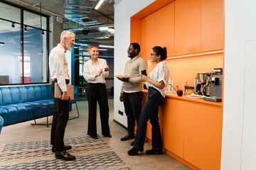 Multiracial colleagues talking and having sandwiches in office