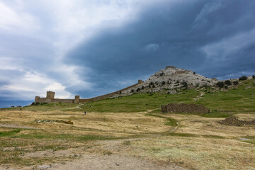 A picturesque view with a stormy sky of the Fortress Mountain and the ancient fortress. Genoese Fortress, Sudak, Crimea