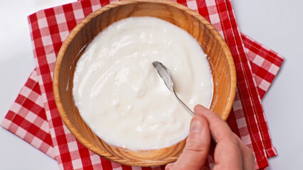 top view of man holding spoon with yogurt near bowl isolated on white