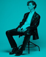 guy in a black leather suit and black shoes.Sit on a chair in black casual shoes.The guy with red...