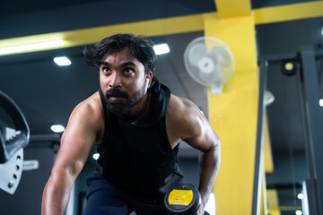 young man busy exercising using dumbells at fitness center - concept of burning fat, bodybuilding and workout center