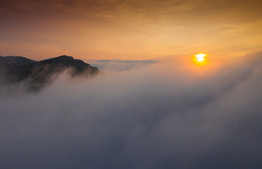 Sunrise over the sea of clouds on top of the mountains. Aerial view with amazing sky color.