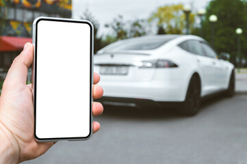 Smartphone mockup in the hands of a man. Against the background of a white electric car.