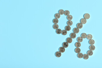 Percent sign made of Ukrainian hryvnia coins on turquoise background, flat lay. Space for text