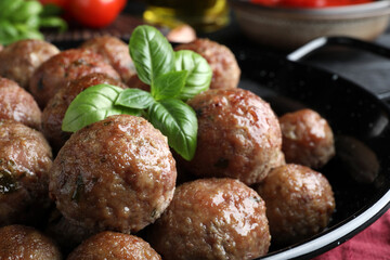 Tasty cooked meatballs and basil on table, closeup