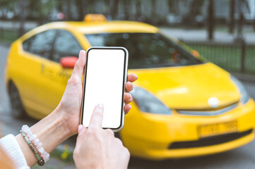 A woman holds a smartphone mockup in her hand, close-up. Against the backdrop of a taxi in the city.
