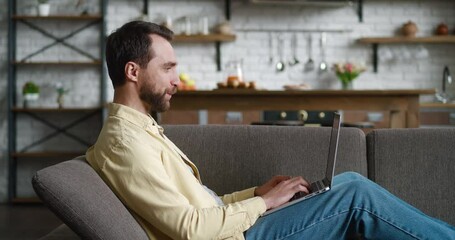 Business man talking with partner in video conference resting on sofa at home. Young male freelancer using laptop computer for online meeting in video call. Working remotely and social isolation. - Powered by Adobe