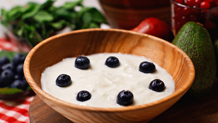 close up of fresh blueberries in wooden bowl with yogurt