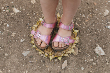 children's feet in sandals stand on a withered sunflower