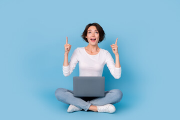 Photo of funny impressed woman wear white shirt legs crossed chatting modern gadget empty space isolated blue color background
