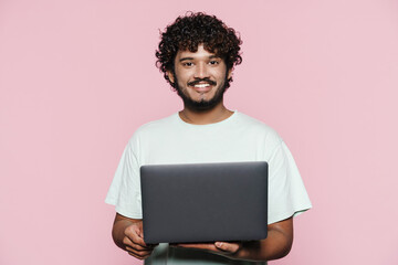 Young middle eastern man smiling while posing with laptop