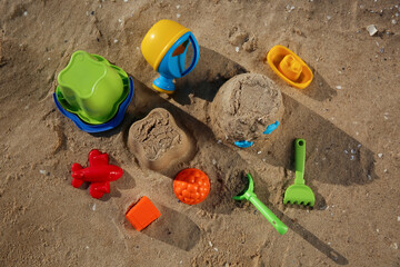 Fototapeta na wymiar Set of plastic beach toys on sand, flat lay. Outdoor play