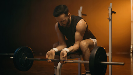 Fototapeta na wymiar Muscular man training with barbell on flat bench on dark background