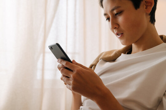 Asian boy with brace using mobile phone at home