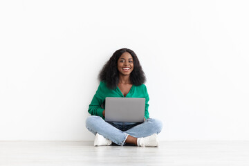 Smiling pretty african american woman with laptop on white