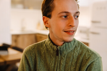 European ginger man smiling and looking aside at home