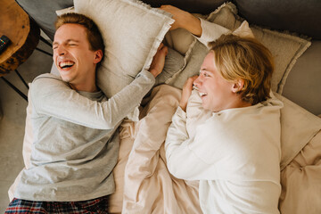 European gay couple laughing and making fun while lying on bed
