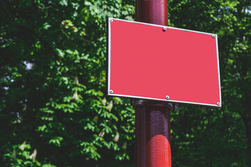 Close-up, Mockup of a red sign on a pole. Against the background of the park.