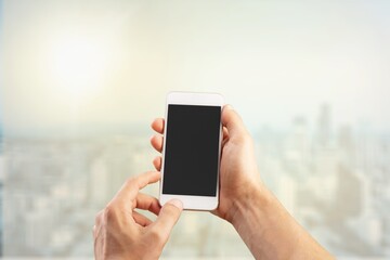 Human hand holding phone with blank screen and cityscape blur background