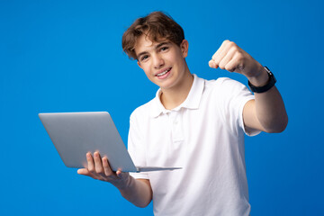 Teenage boy using laptop against blue background