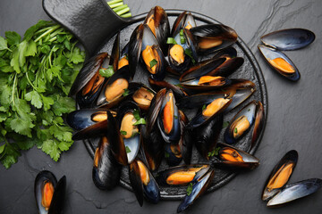 Serving board with cooked mussels and parsley on slate table, flat lay