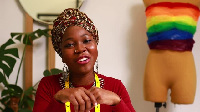 tanzanian woman with snake print turban over hear creating a colorful dress for pride parade in her dressmaking showroom