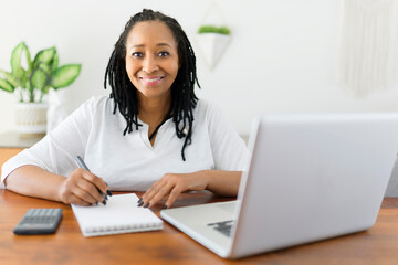 black woman using computer in modern kitchen interior