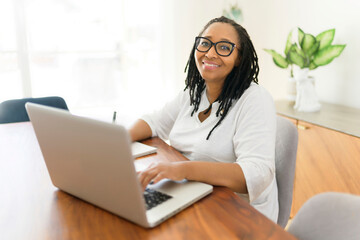 black woman using computer in modern kitchen interior