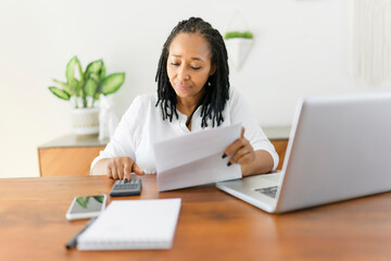 black woman using computer in modern kitchen interior