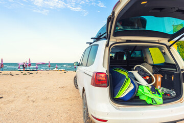 Back view young adult male surfer in wetsuit put out surf board kite equipment on sand beach from...