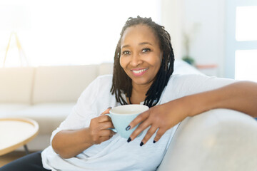 Portrait of an african woman sit on the sofa with coffee