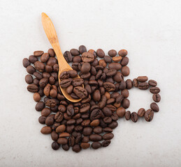 A cup of coffee beans with a wooden spoon inside. Top view