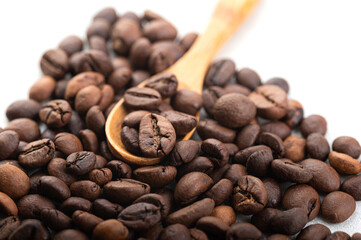 Coffee beans in a wooden spoon on a slide of coffee beans. Close-up