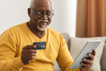 African Man Using Card And Tablet Shopping Online At Home