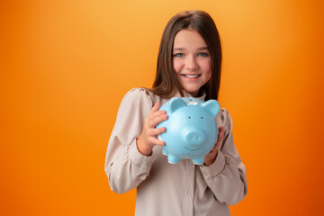 Fototapeta na wymiar Teen girl with piggy bank on orange color background.