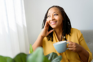Portrait of an african woman sit on the sofa with coffee