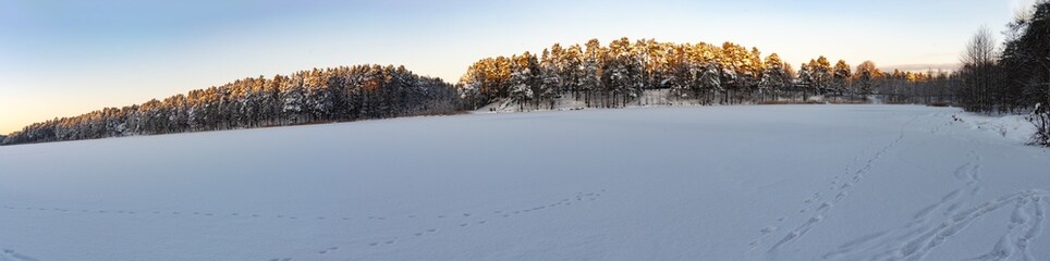 Panorama of sunrise on frozen lake. Winter landscape.