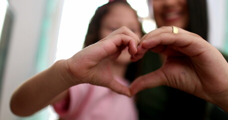 Mother and child girl doing heart sign symbol with hands