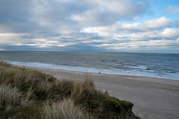 Fototapeta na wymiar Eine Person steht im Winter am Strand von Kampen Insel Sylt und schaut auf das Meer 