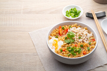 Instant noodle soup with minced pork and boiled egg in white bowl on wood table.with copy space