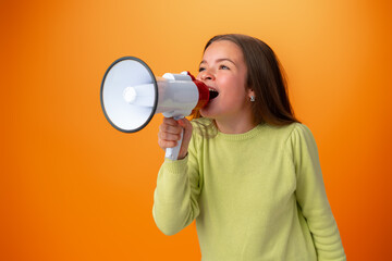 Fototapeta na wymiar Teen girl making announcement with megaphone against orange background